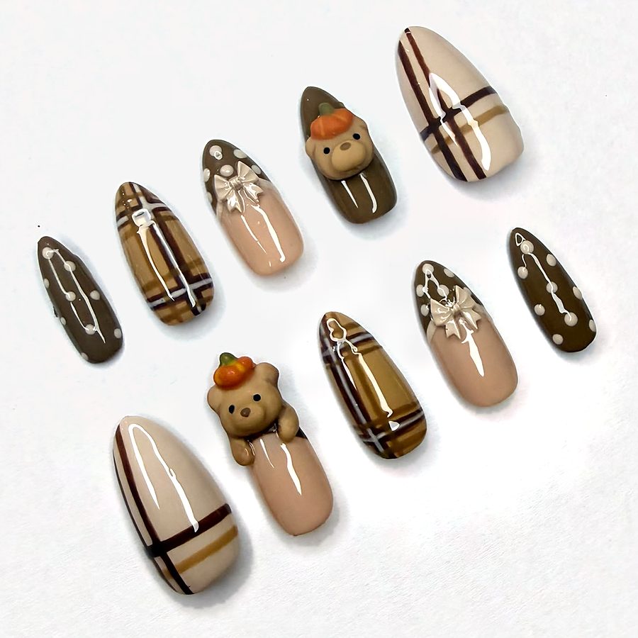 A press on nail set in chocolate brown and nude plaid with pearl dots, satin bows and teddy bears wearing tiny pumpkins